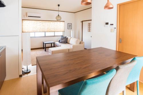 a dining room with a wooden table and blue chairs at Tino Kawara in Osaka