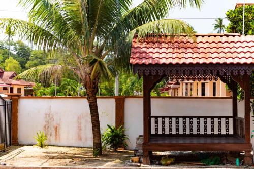 a bench in front of a house with a palm tree at Beachland Guesthouse in Kuala Terengganu