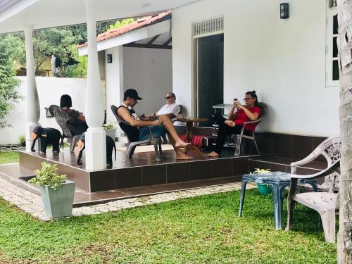 a group of people sitting on the porch of a house at White Villa Airport Transit Hotel in Katunayake
