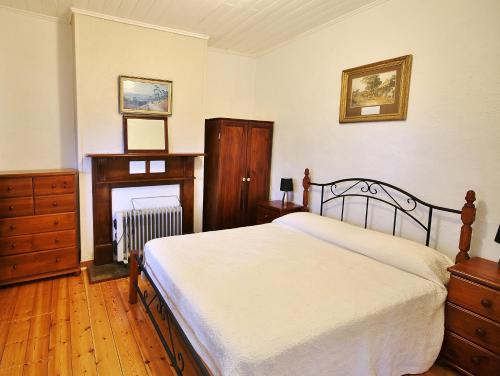 a bedroom with a bed and a dresser and a fireplace at Stonewall Cottage in Moonta