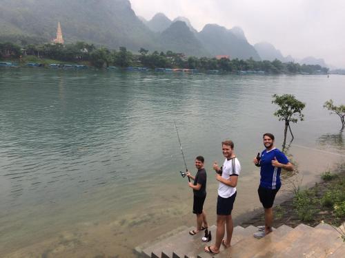 three men standing on the shore of a lake fishing at Carambola Bungalow in Phong Nha