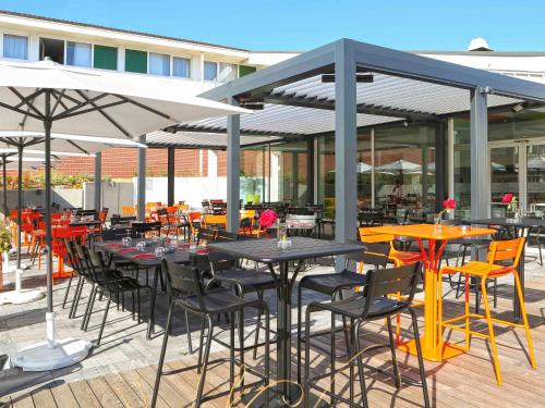 a group of tables and chairs with umbrellas on a patio at ibis Styles Nancy Sud in Houdemont