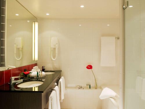 e bagno con lavandino, specchio e vasca. di Novotel Paris Roissy CDG Convention a Roissy en France