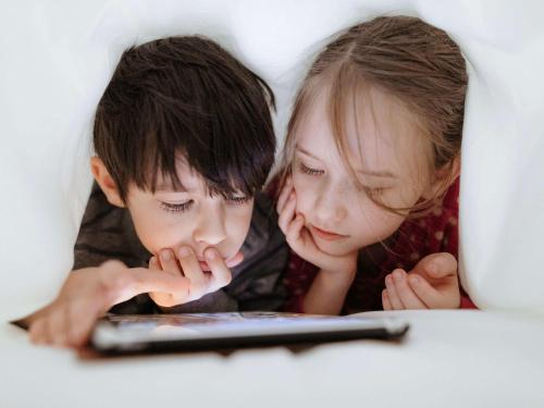 two children looking at a tablet computer in a bed at Mercure Paris Boulogne in Boulogne-Billancourt