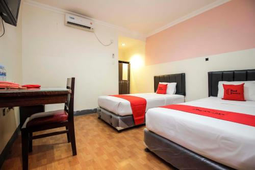 a hotel room with two beds and a desk at RedDoorz near Bethesda Manado in Manado