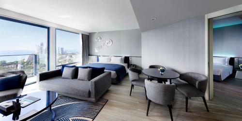 a hotel room with a bed and a table and chairs at Grande Centre Point Pattaya in Pattaya Central