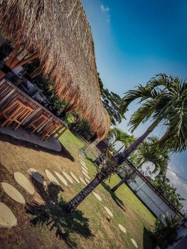 a large straw umbrella and palm trees on a beach at Clandestino Hostel Canggu in Canggu
