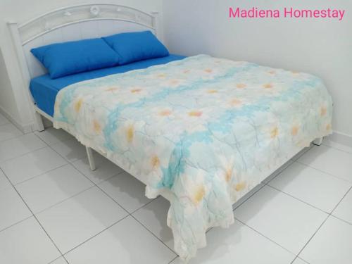 a bed with a blue comforter on top of it at Madiena Homestay in Kampung Gurun