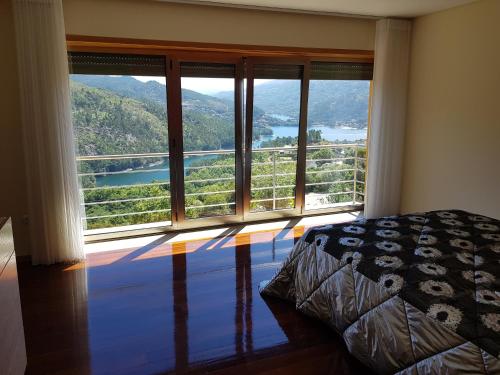 a bedroom with a large window with a view at Merck Villa Gerês in Rio Caldo