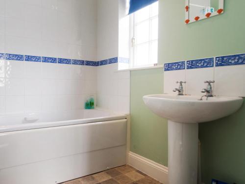 een badkamer met een wastafel en een bad bij 1 Bell Lodge, Thorpeness in Thorpeness