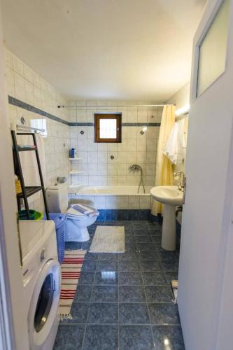 a bathroom with a tub and a toilet and a sink at Rodomelo House - 3 Bedrooms in Leonidio