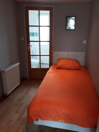 a bedroom with a bed with an orange comforter at Hotel De La Gare in Sainte-Gauburge-Sainte-Colombe