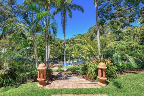 a path through a park with palm trees at Sensom Boutique Bed and Breakfast in Coffs Harbour