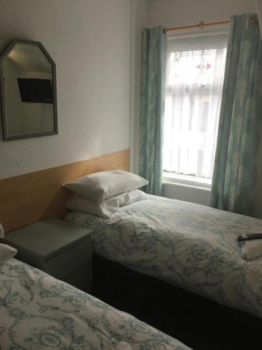 a bedroom with two beds and a mirror and a window at The Danescourt in Blackpool