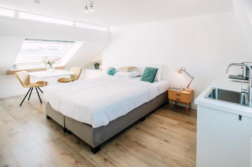 een slaapkamer met een bed, een wastafel en een tafel bij Zylt Zandvoort in Zandvoort