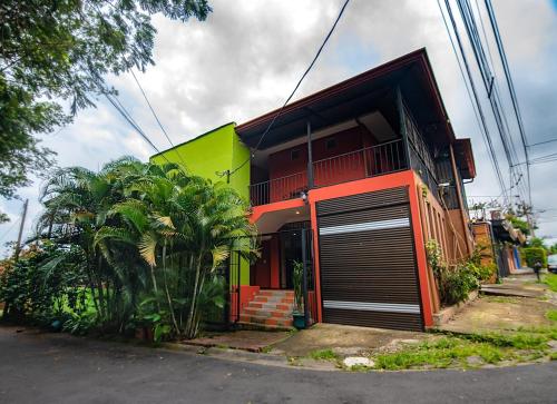 une maison colorée avec une porte de garage devant elle dans l'établissement Melrost Airport Bed & Breakfast, à Alajuela