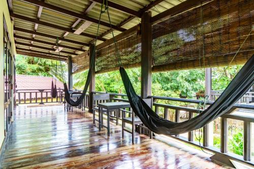 a porch with hammocks and a table and chairs at Mr Tho's Bungalows in Don Det