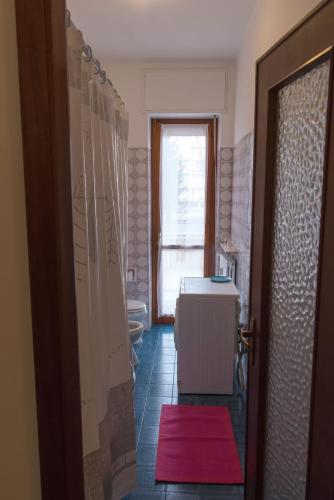 a bathroom with a red rug on the floor and a doorway at Luminoso bilocale in Alessandria