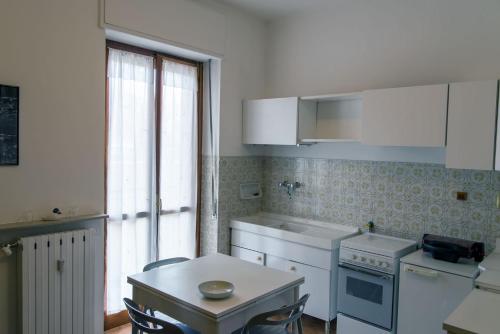 a kitchen with white appliances and a table and a window at Luminoso bilocale in Alessandria
