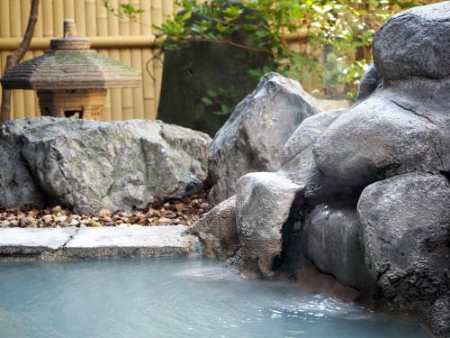a water feature in a garden with rocks and a birdbath at Kashoutei Hanaya in Noboribetsu