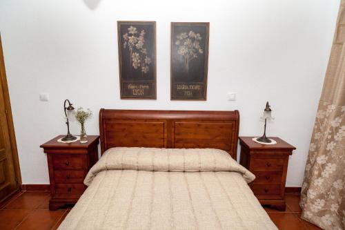 西古恩薩的住宿－Casa Rural El Tinte，一间卧室配有一张带2个床头柜和2张照片的床