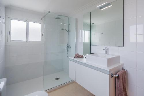 a white bathroom with a sink and a shower at Villa Maria in El Port