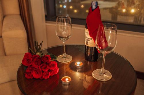 a table with two glasses and a bottle of wine and roses at Muong Thanh Luxury Bac Ninh Hotel in Bắc Ninh