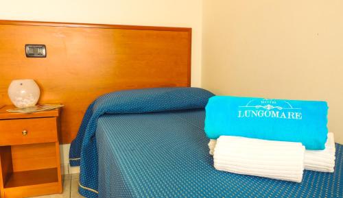 a room with a blue bed with a wooden head board at Hotel Lungomare in Reggio Calabria