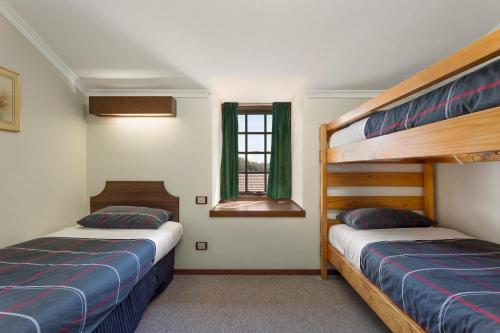a bedroom with two bunk beds and a window at Village Family Motor Inn in Launceston