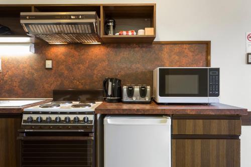 a kitchen with a stove and a microwave at Village Family Motor Inn in Launceston
