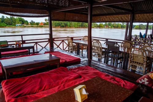 a boat with tables and chairs on a river at Mr Tho's Bungalows in Don Det