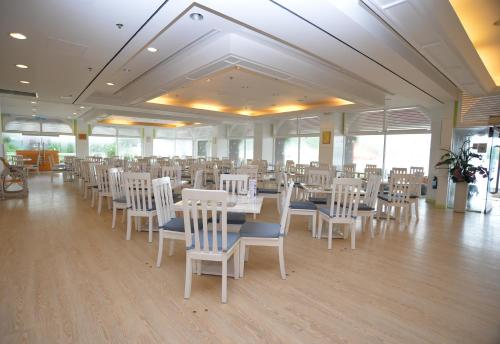 un salón de banquetes con mesas blancas y sillas blancas en Silvermine Beach Resort en Hong Kong