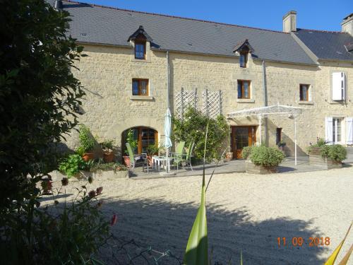 a large stone building with a courtyard in front of it at La ferme aux chats in Formigny