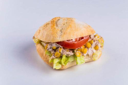 a sandwich with corn and a tomato on a bun at Retro Hostel in Cluj-Napoca
