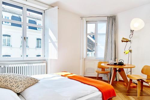 a bedroom with a bed and a table and windows at Consum Boutique Hotel in Basel