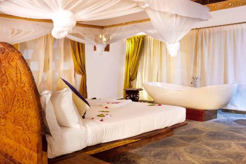 a bedroom with a white bed and a tub at The Island - Pongwe Lodge in Pongwe