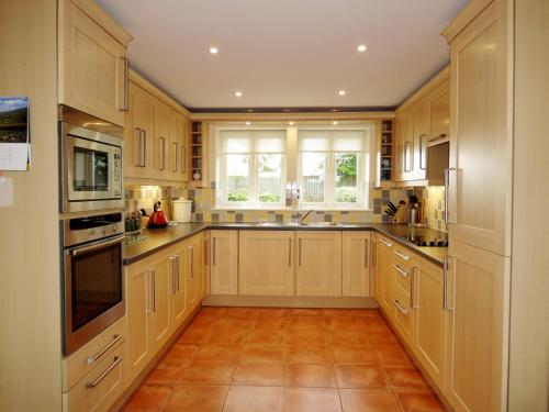 a kitchen with wooden cabinets and a large window at Meadow View, Near Aldeburgh in Aldringham