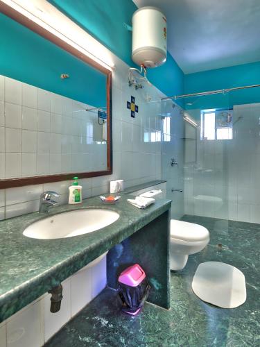 a bathroom with a sink and a toilet and a mirror at Ikaki Niwas - A Heritage Boutique Hotel in Jaipur