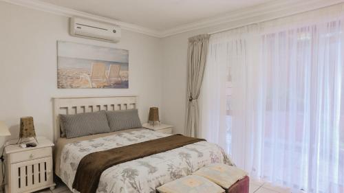 a white bedroom with a bed and a window at Suzy's Place in Port Edward