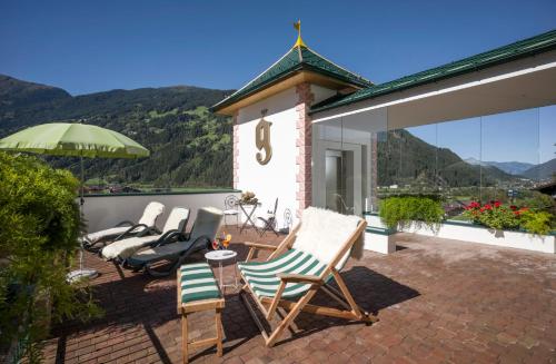 a group of chairs on a patio with mountains in the background at Aparthotel Gallahaus in Zell am Ziller