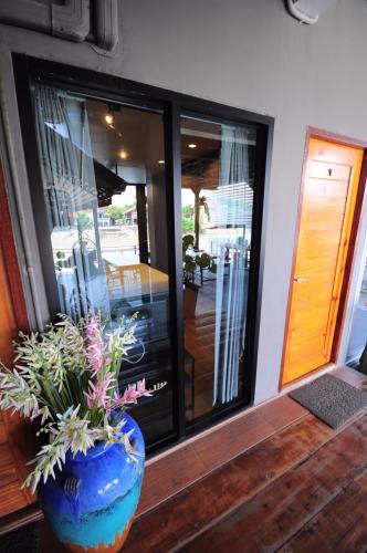 a vase with flowers in it sitting on a porch at Baan Keang Chon Ayutthaya บ้านเคียงชล อยุธยา in Phra Nakhon Si Ayutthaya