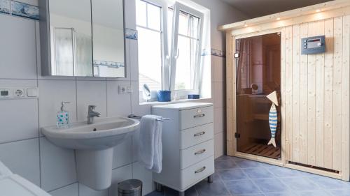 ein weißes Bad mit einem Waschbecken und einer Dusche in der Unterkunft Ferienwohnung Villa Bullerbü in Sankt Peter-Ording