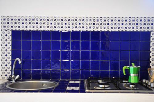a blue tiled wall above a sink in a kitchen at Casa Capiciana - punta rotolo in Milazzo