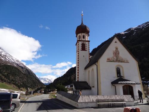 a church with a clock tower in the mountains at Haus Eberhard in Vent