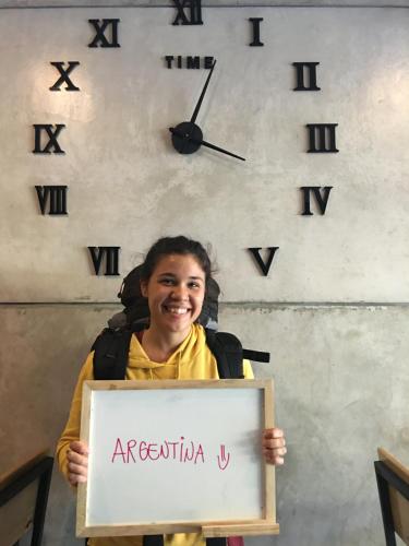 a girl holding a sign in front of a clock at Doze Hostel in Chiang Mai
