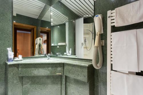 La salle de bains est pourvue d'un lavabo et d'un grand miroir. dans l'établissement Albergo Il Cacciatore, à Spello