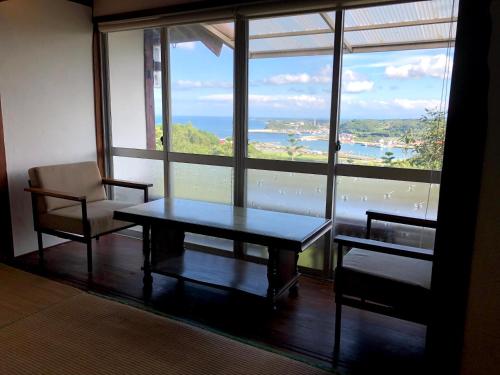 a room with a table and chairs and a large window at Guesthouse Wasabi in Iki