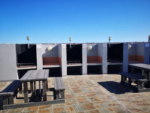 two benches and tables on the roof of a building at Vista Bonita Apartments in Mossel Bay