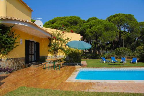 uma casa com piscina, cadeiras e guarda-sol em Quinta Vita - Vila Uva em Almancil