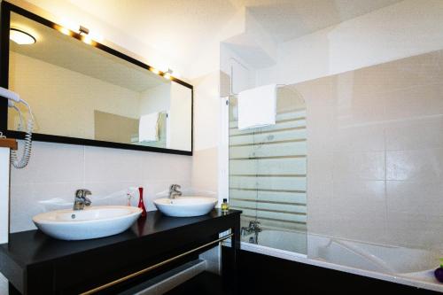 a bathroom with two sinks and a mirror and a tub at Résidence Néméa L'Aigle Bleu in Briançon